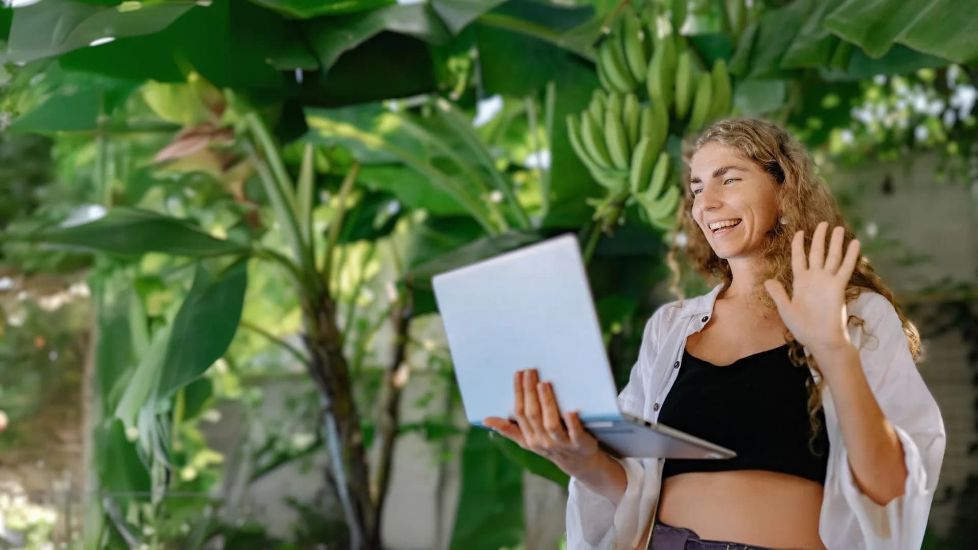 mujer con una laptop en mano en una reunión virtual